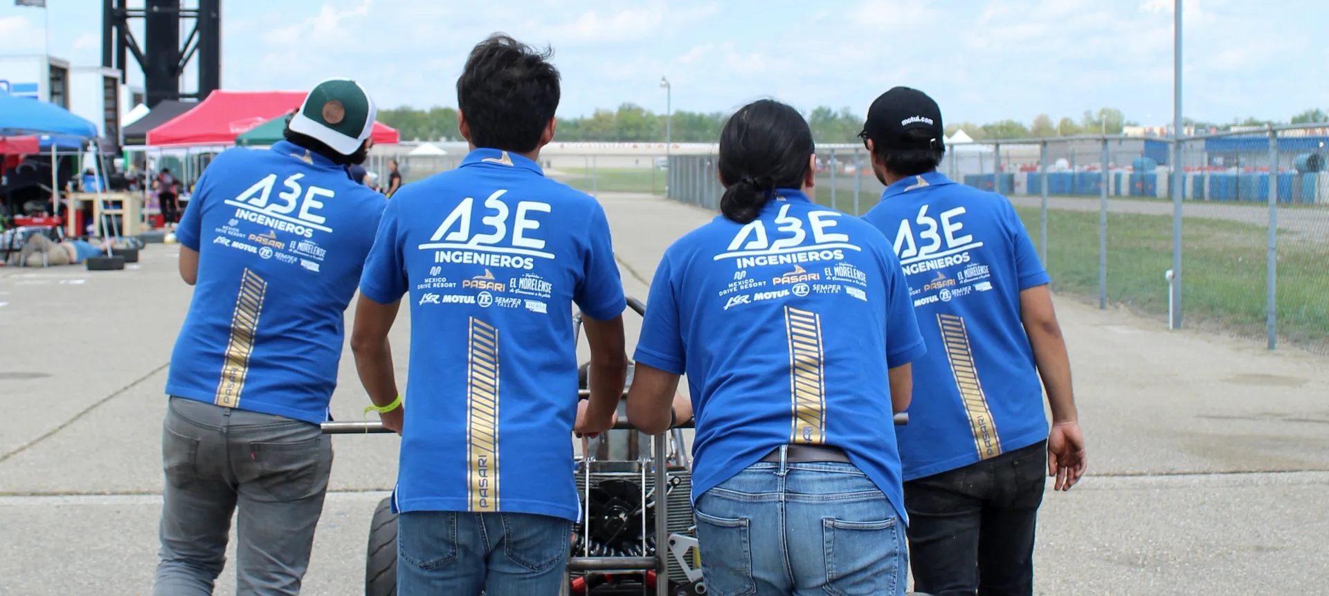 Cuatro integrantes del equipo PASARI empujando un monoplaza de competencia en pista