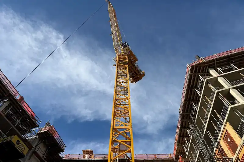Grúa torre elevándose entre estructuras en una obra en construcción