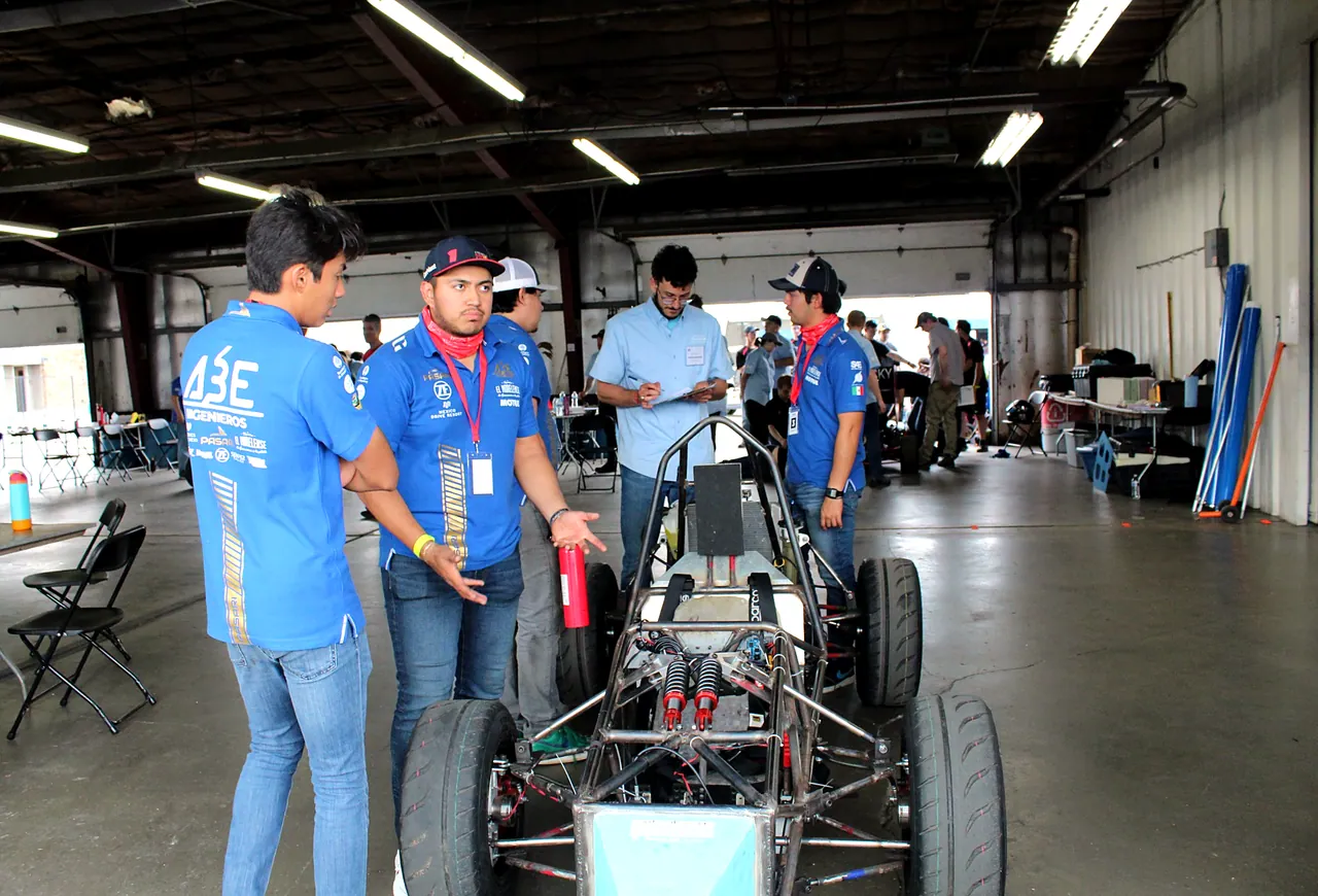 Estudiantes revisando sistemas del monoplaza en el garage de competencia