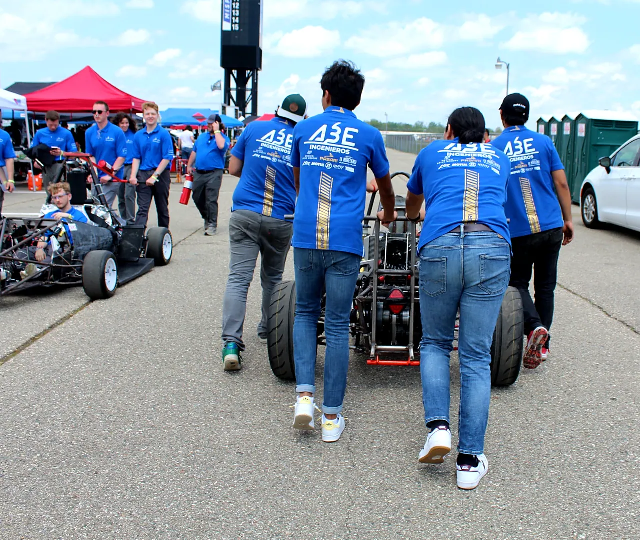 Integrantes del equipo empujando el monoplaza por el paddock